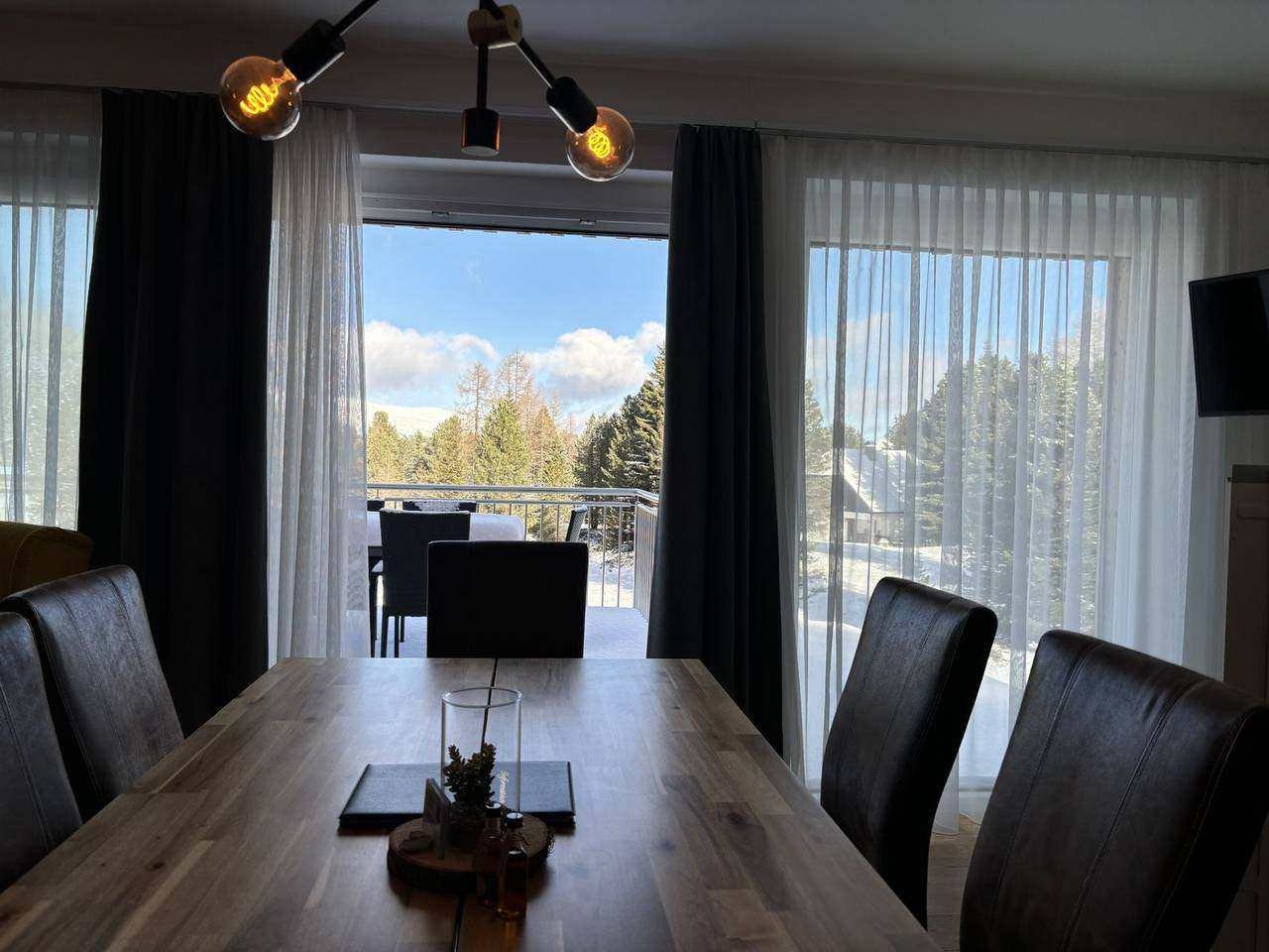 View from the dining table to the snowy terrace – Almzeit chalet apartment, Turracher Höhe