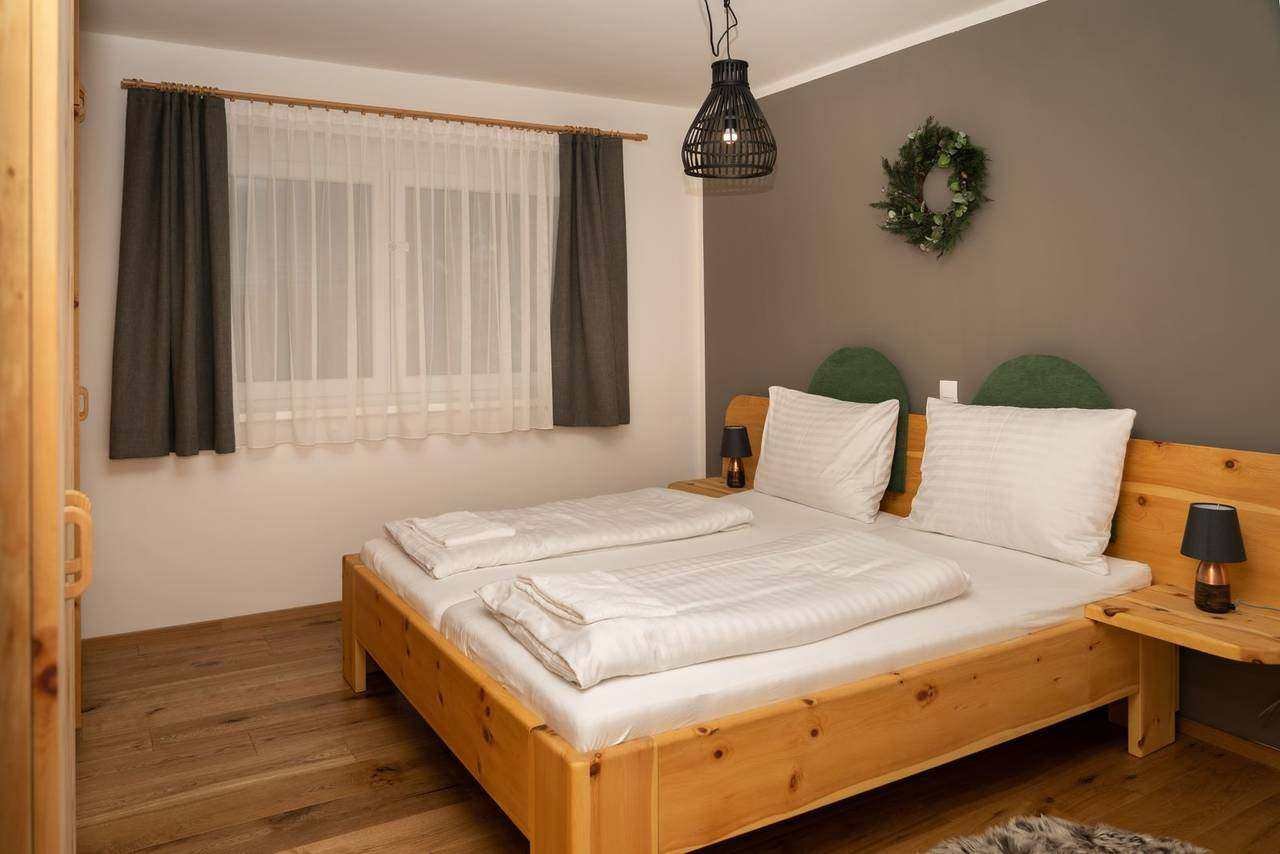 Bedroom with wooden double bed – Almzeit chalet apartment, Turracher Höhe