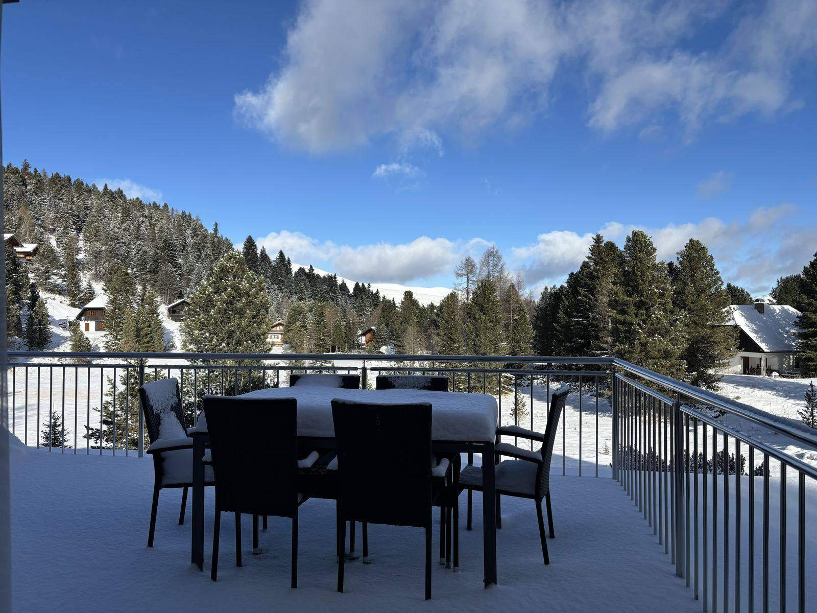 Terrace of the Almzeit chalet apartment in winter with snow and stone-pine forest, Turracher Höhe