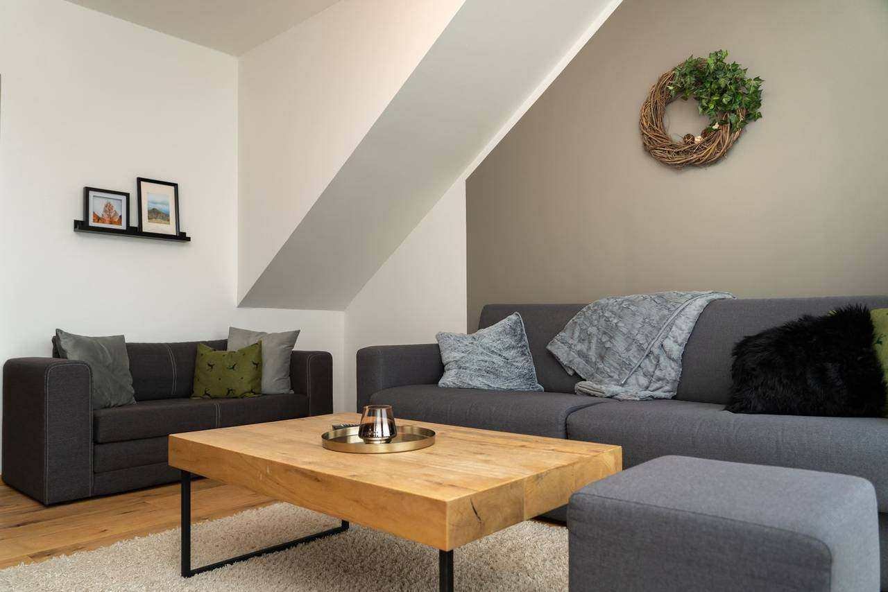 Living room with sofa under the sloping roof – Almzeit chalet apartment, Turracher Höhe