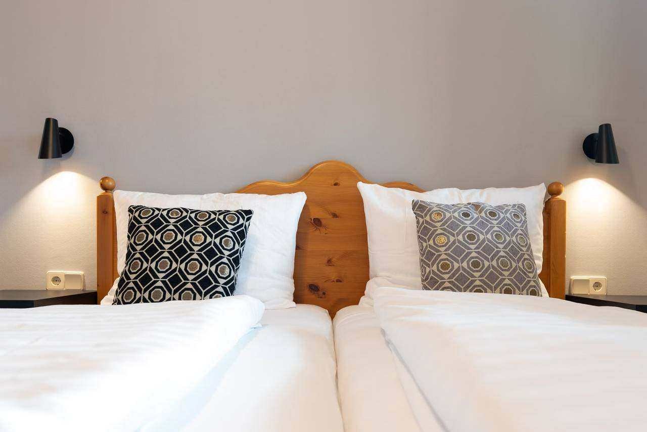 Double bed with wooden headboard and fresh linen – holiday apartment Gerlitzen Alpe