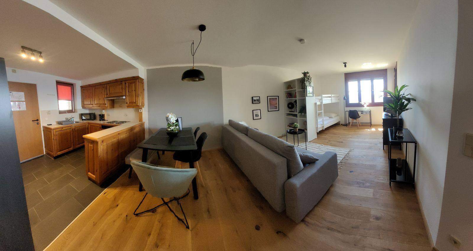 Panorama of the living space with kitchen, sofa and bunk bed – holiday apartment Gerlitzen Alpe