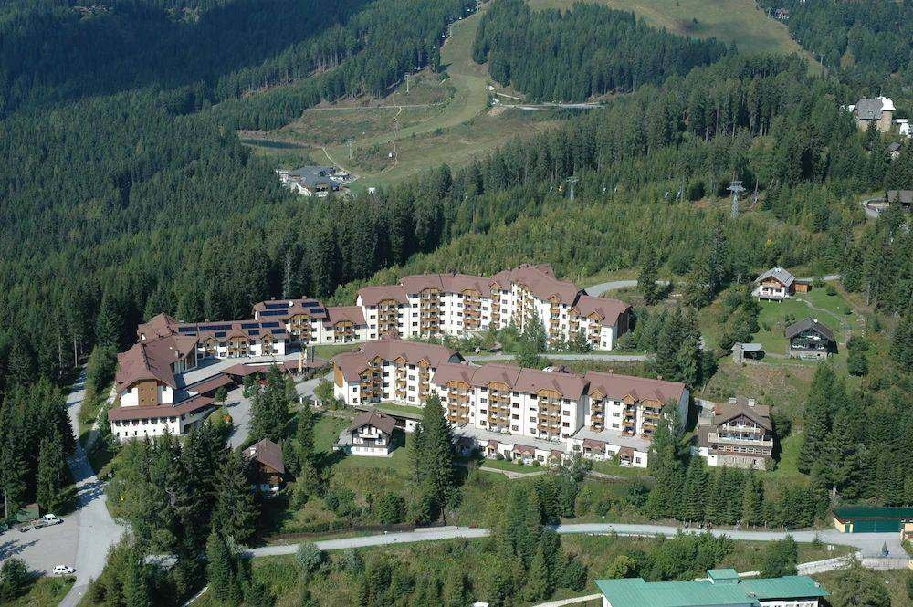 Aerial view of Kanzelhöhe in summer: holiday apartments, ski slope and forest on the Gerlitzen Alpe