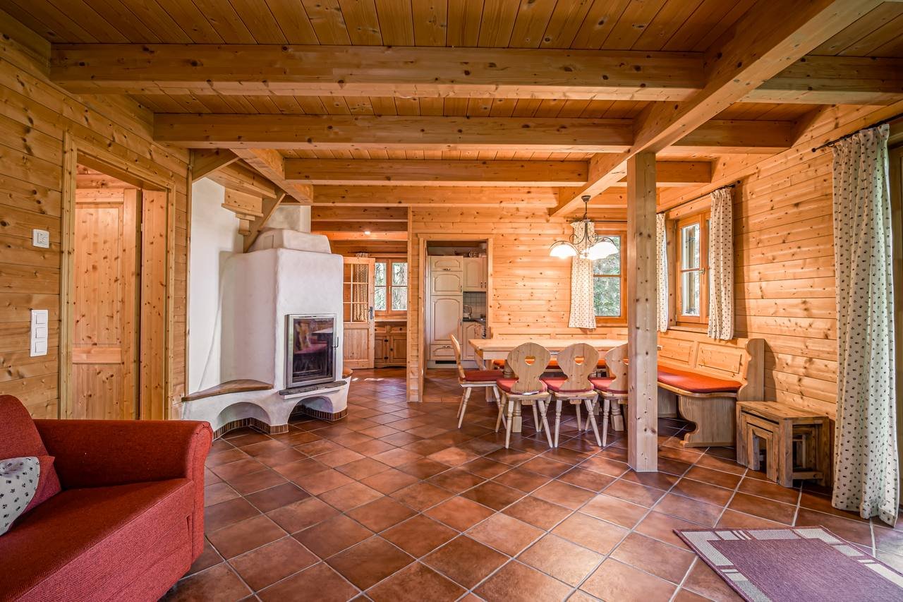Living space with sofa, dining table and tiled stove – Chalet Murmeltier